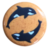 1" button of two orca whales against a mottled orange background