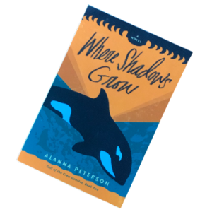 vinyl sticker of where shadows grow cover. an orca whale dives into a turquoise ocean beneath an orange sunset.