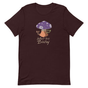 Oxblood black short-sleeve t-shirt featuring a purple toadstool mushroom with four smaller mushrooms budding from the stipe. Text underneath reads "What We Bury."